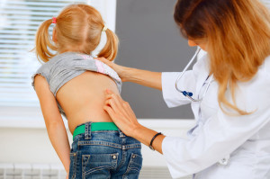 33514610 - pediatrician examining little girl with back problems.